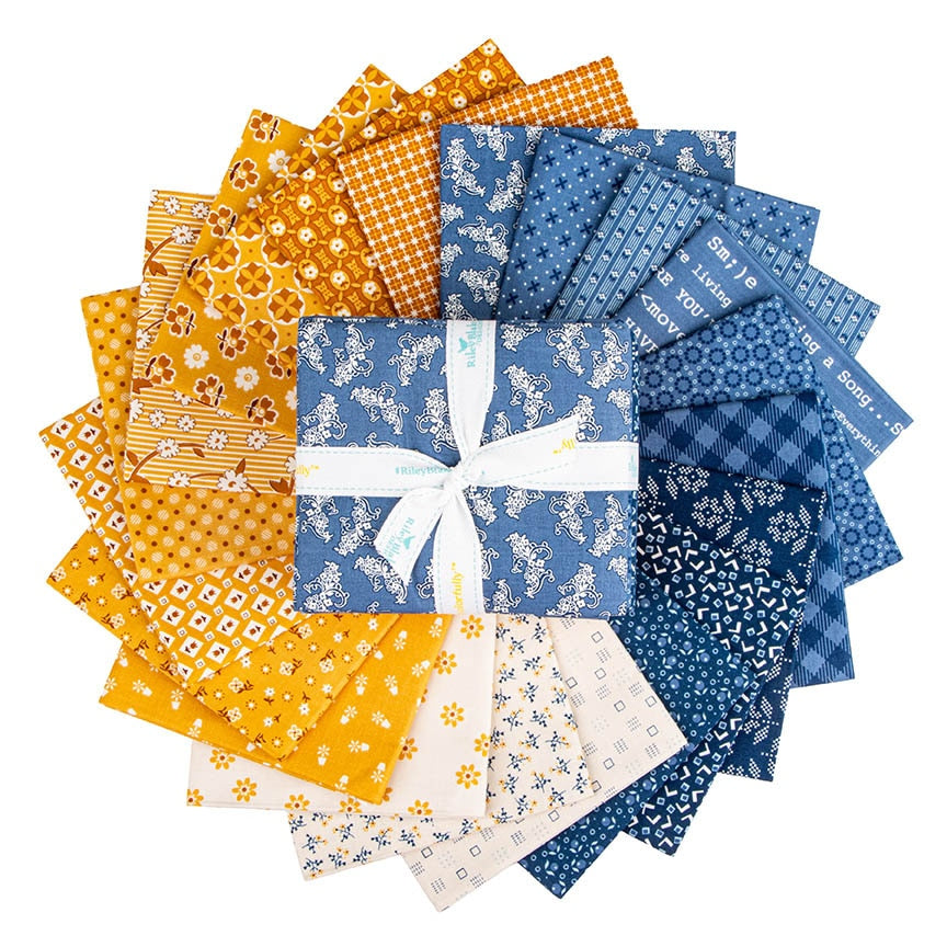 Denim & Daisy fat quarters by Lori Holt fanned out – daisy florals, plaids and text prints in blue and gold