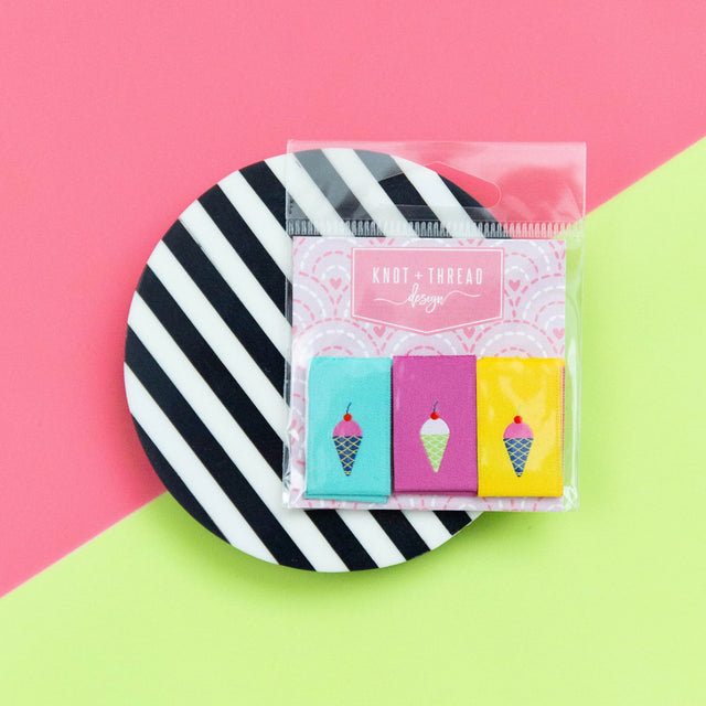 Pack of colorful ice cream-themed woven tags on a black and white striped background with a pink and green geometric pattern.