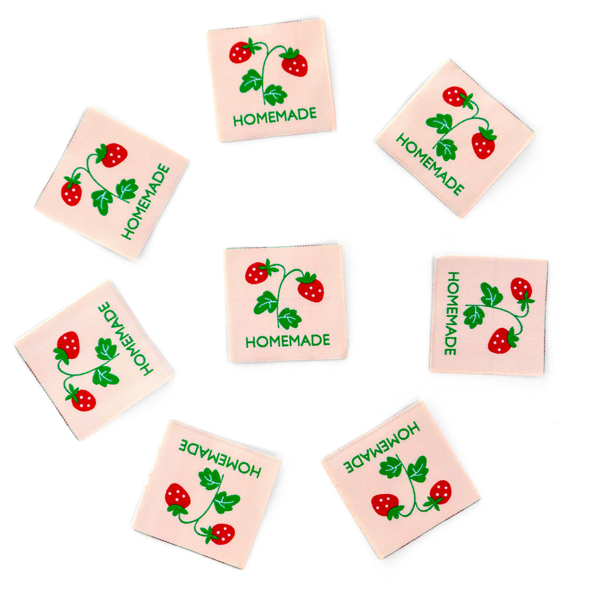 Set of small square fabric labels with strawberry design and 'Homemade' text on a white background